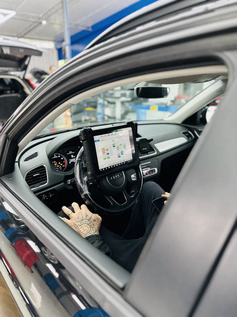 Interior de um Audi, com técnico segurando um tablet com a agenda de serviço no volante.