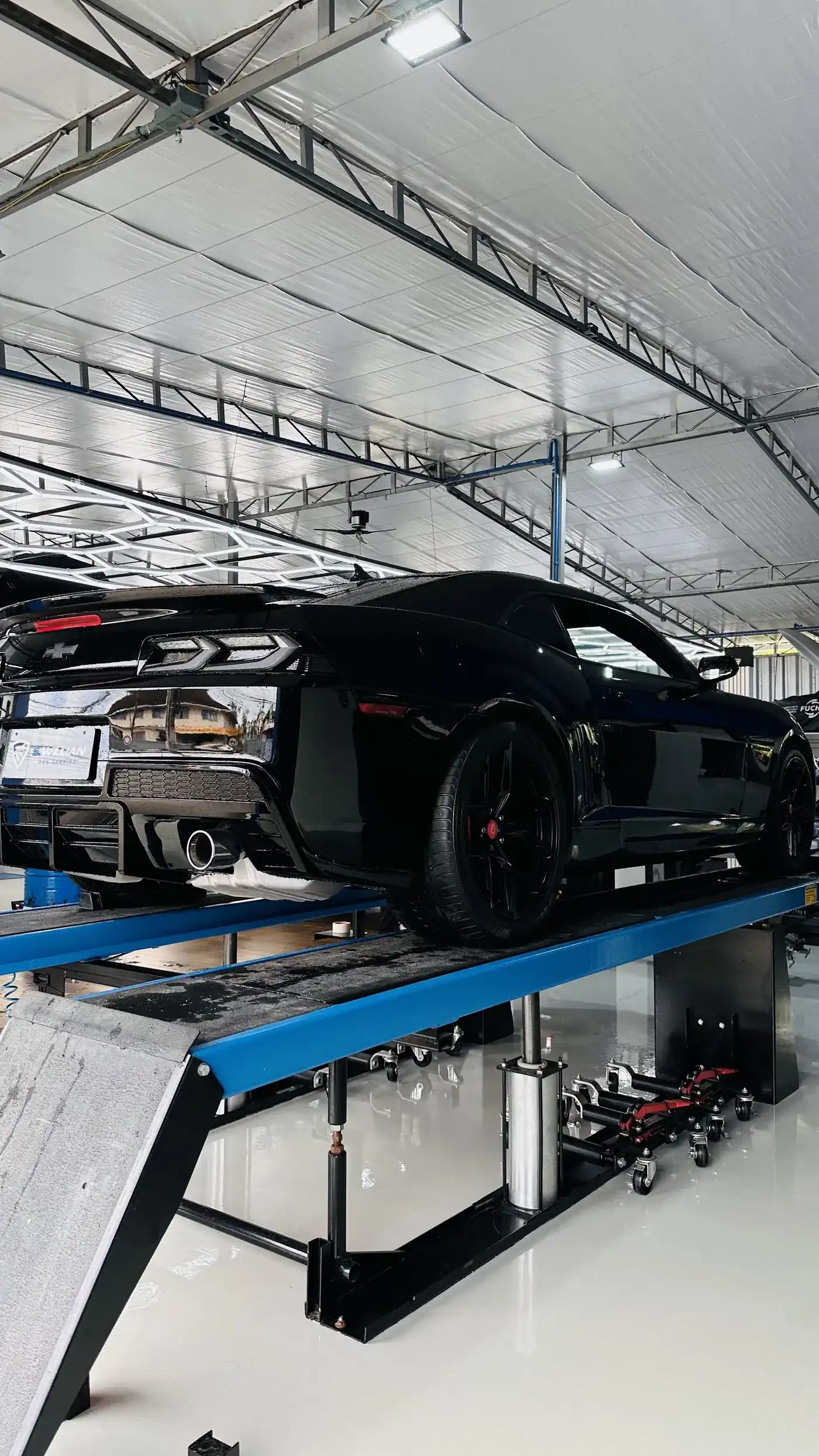 Chevrolet Camaro preto na traseira sobre o elevador de quatro colunas