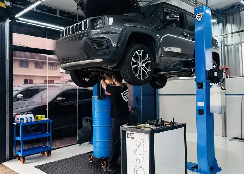 Jeep Renegade no elevador com o técnico trabalhando na suspensão.
