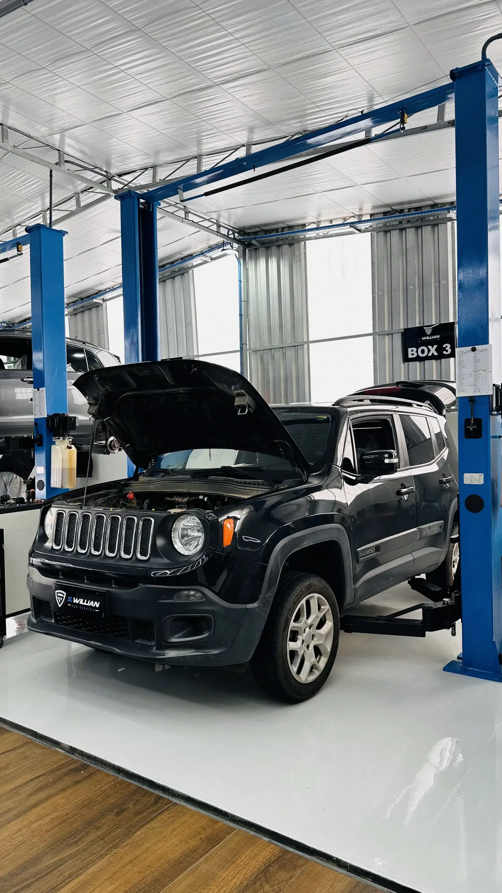 Jeep Renegade com o capô aberto no elevador da oficina, para troca de óleo.