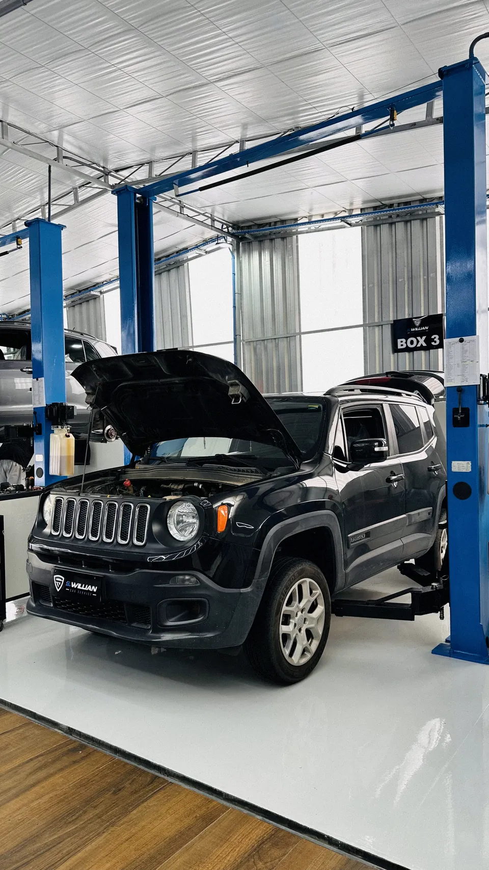 Jeep Renegade com o capô aberto no elevador da oficina, para troca de óleo.
