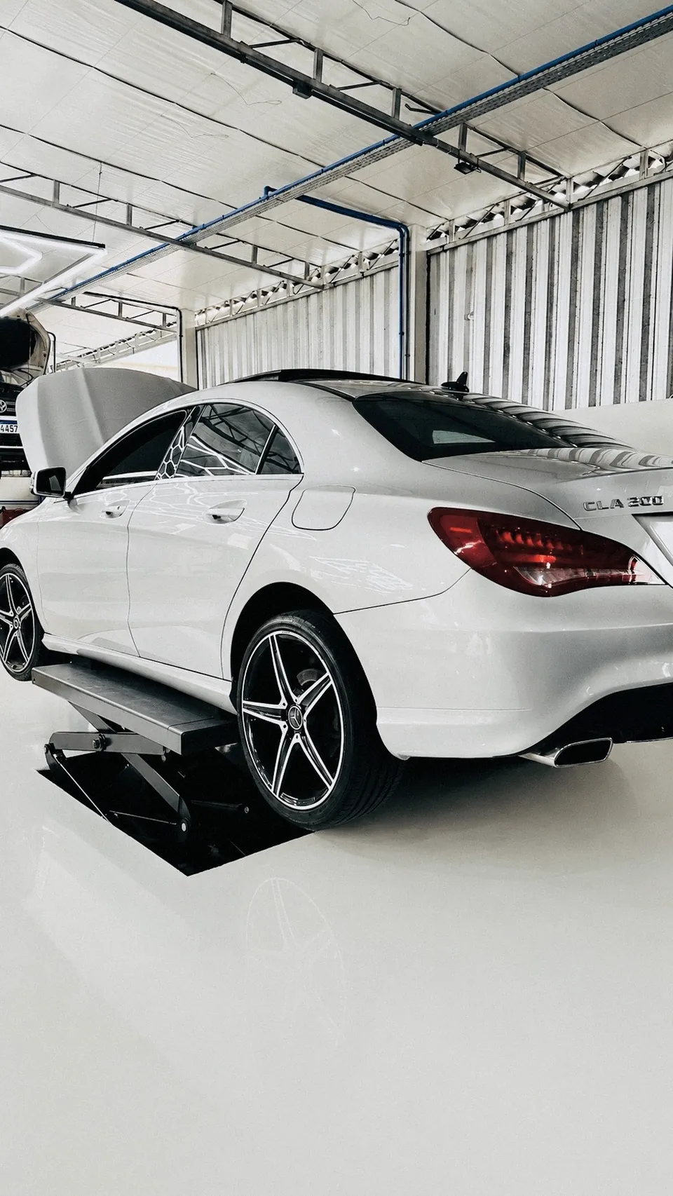 Mercedes-Benz CLA 200 visto de trás no alinhador de rodas, sob teto industrial reto.