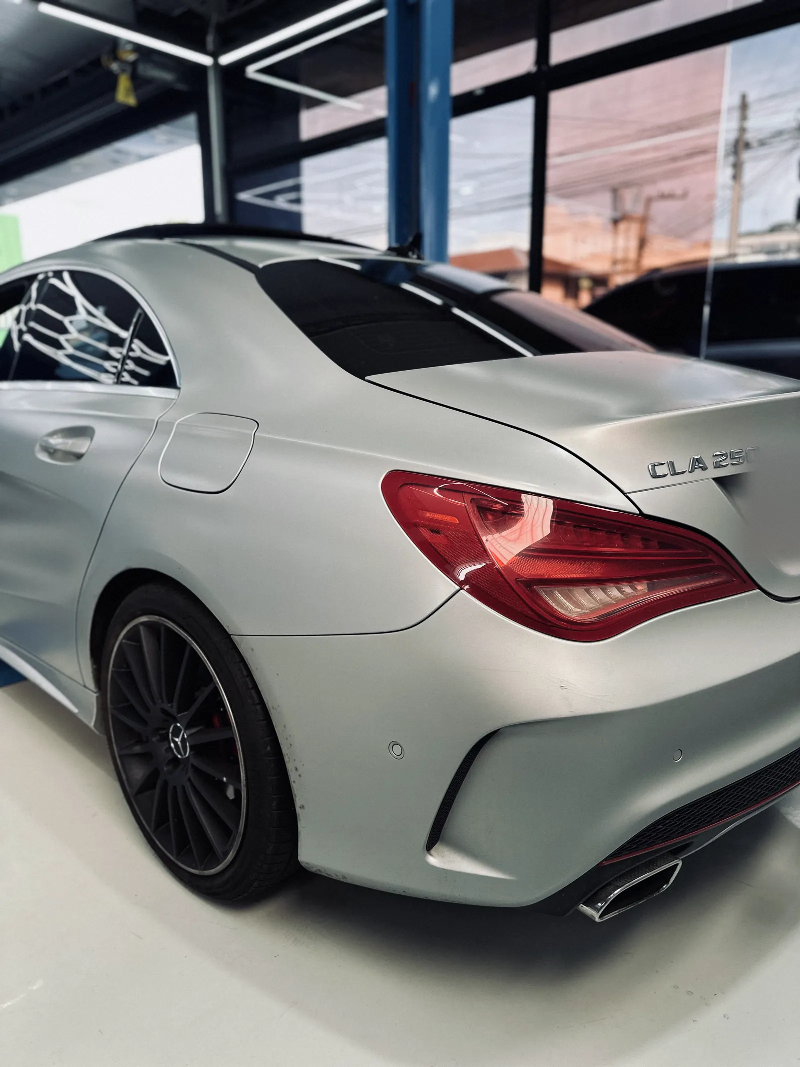 Mercedes-Benz CLA 250 prata visto de trás, elevador ao fundo