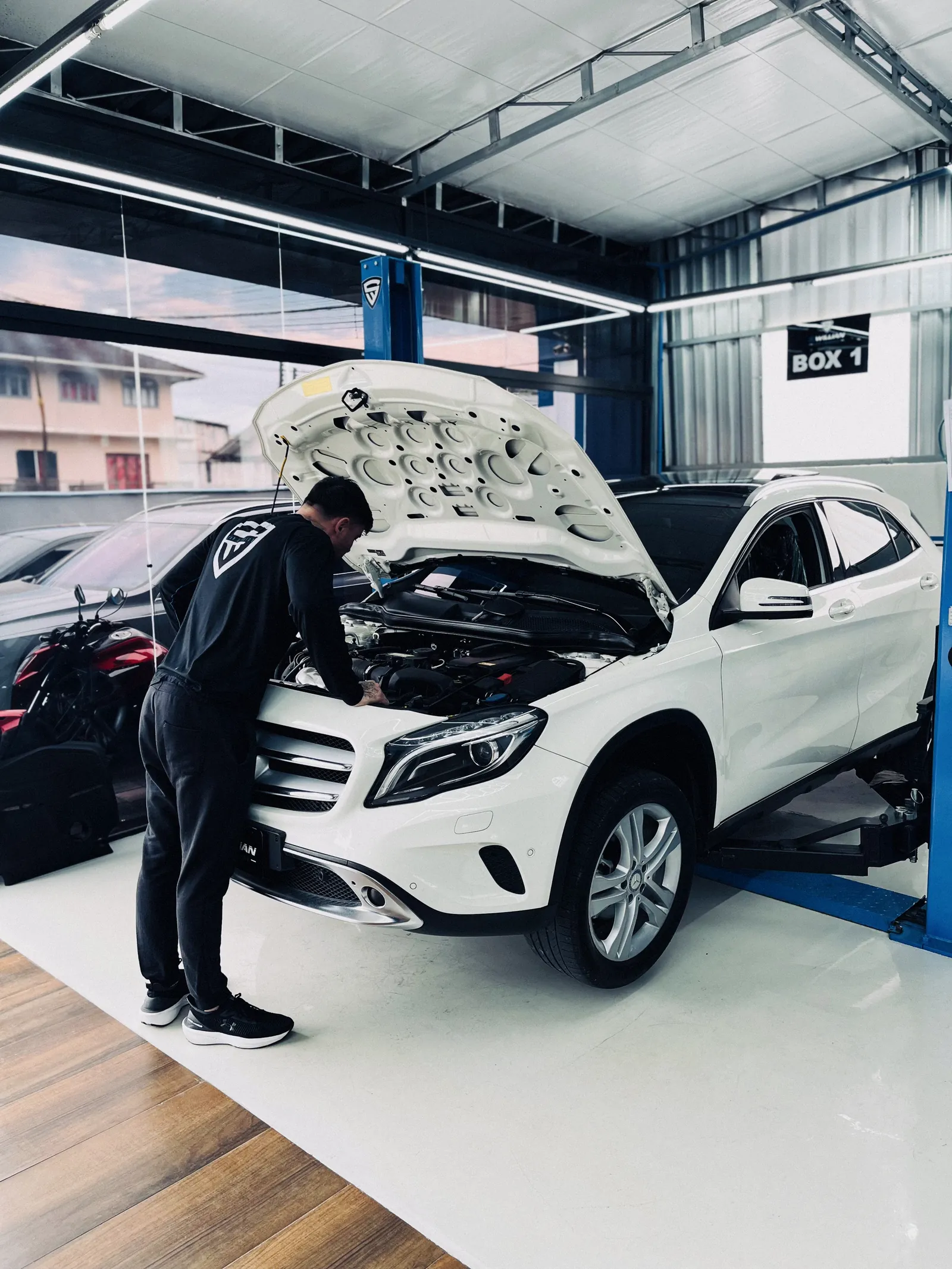 Técnico debruçado sobre o motor de um Mercedes-Benz GLA, avaliando antes do diagnóstico.