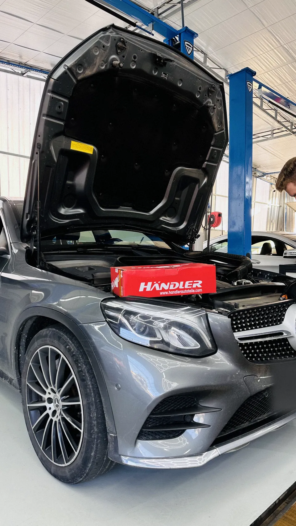 Mercedes-Benz GLC com o capô aberto e caixa de ferramentas sobre o motor, na oficina.
