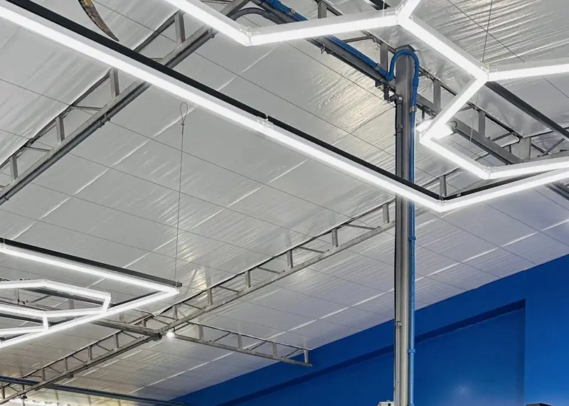 Teto hexagonal com iluminação em LED sobre os boxes da oficina, vista de outro ângulo do salão de serviço.