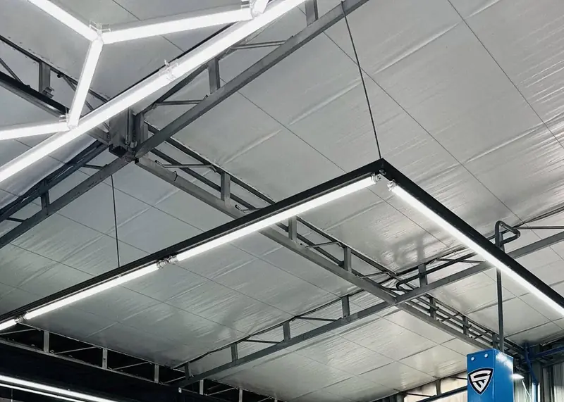 Estrutura do teto hexagonal em LED sobre um dos boxes da oficina, com o escudo da S. Willian na coluna do elevador.