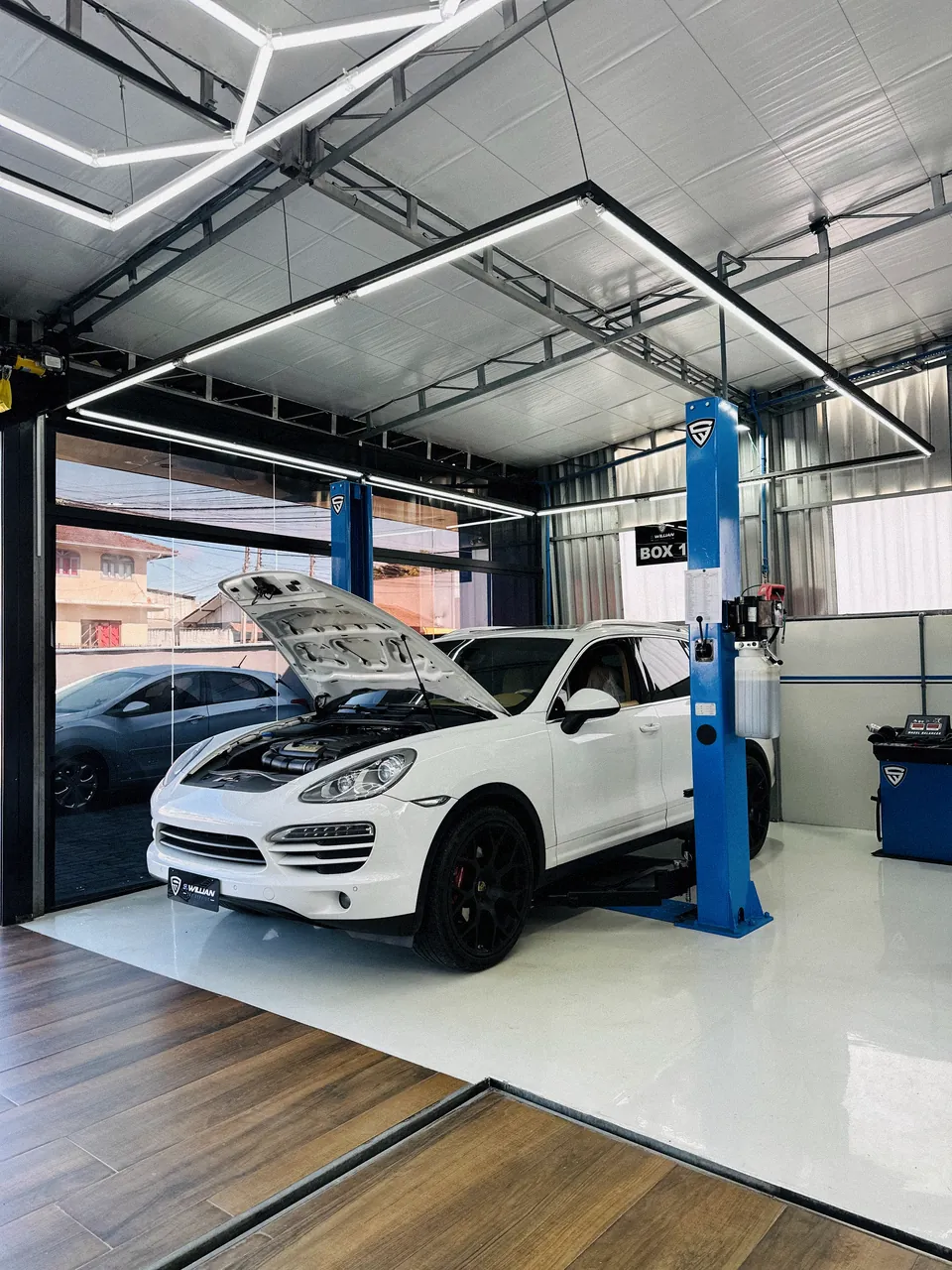 Porsche Cayenne com o capô aberto no elevador da oficina, motor à vista.