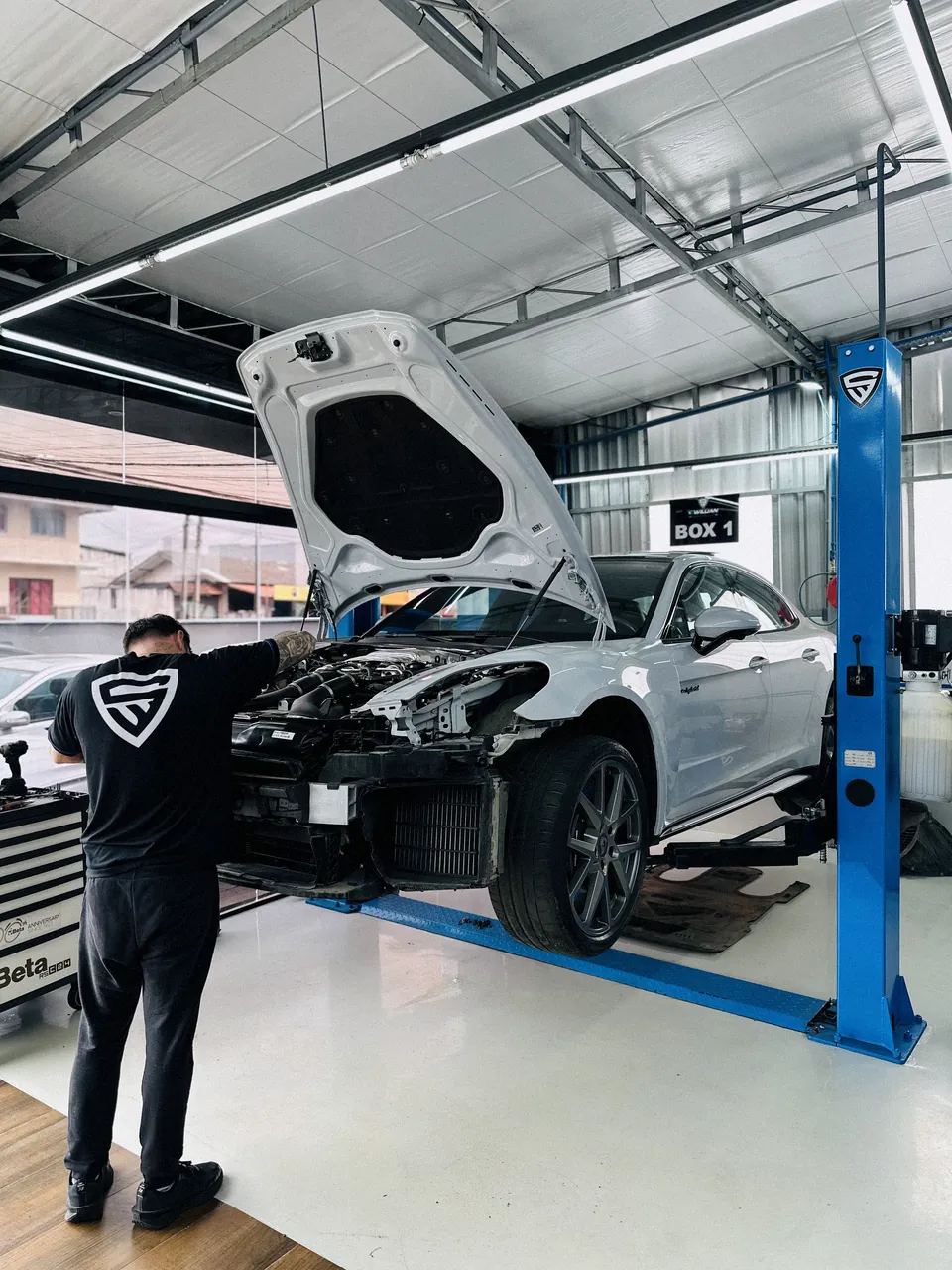 Técnico da oficina trabalhando numa Porsche com o para-choque removido.