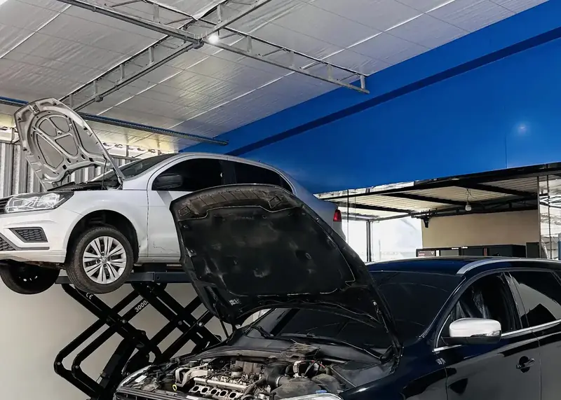Volvo XC60 preto e prata sob o teto hexagonal de LED da oficina.