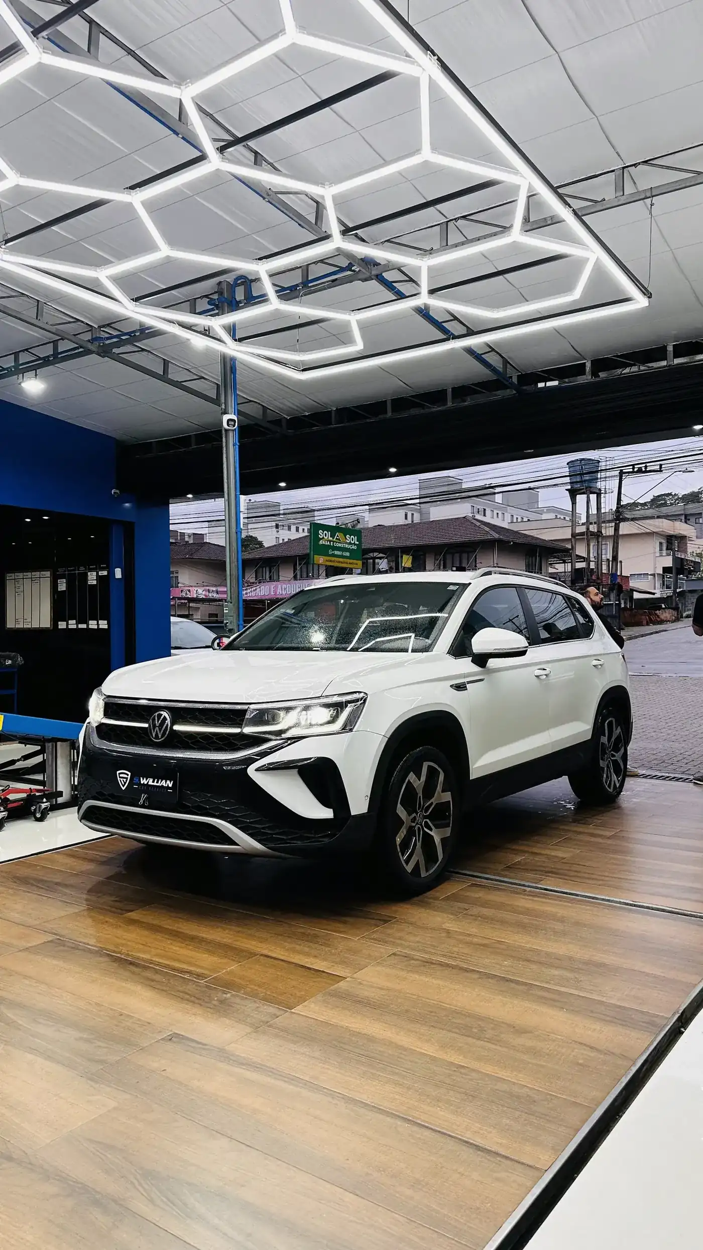 Volkswagen Taos branco com dianteira em três quartos, teto hexagonal de LED, piso de madeira